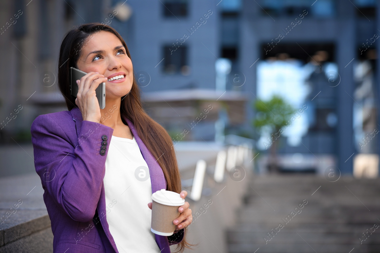 Photo of Beautiful businesswoman with cup of coffee talking on phone outdoors. Space for text