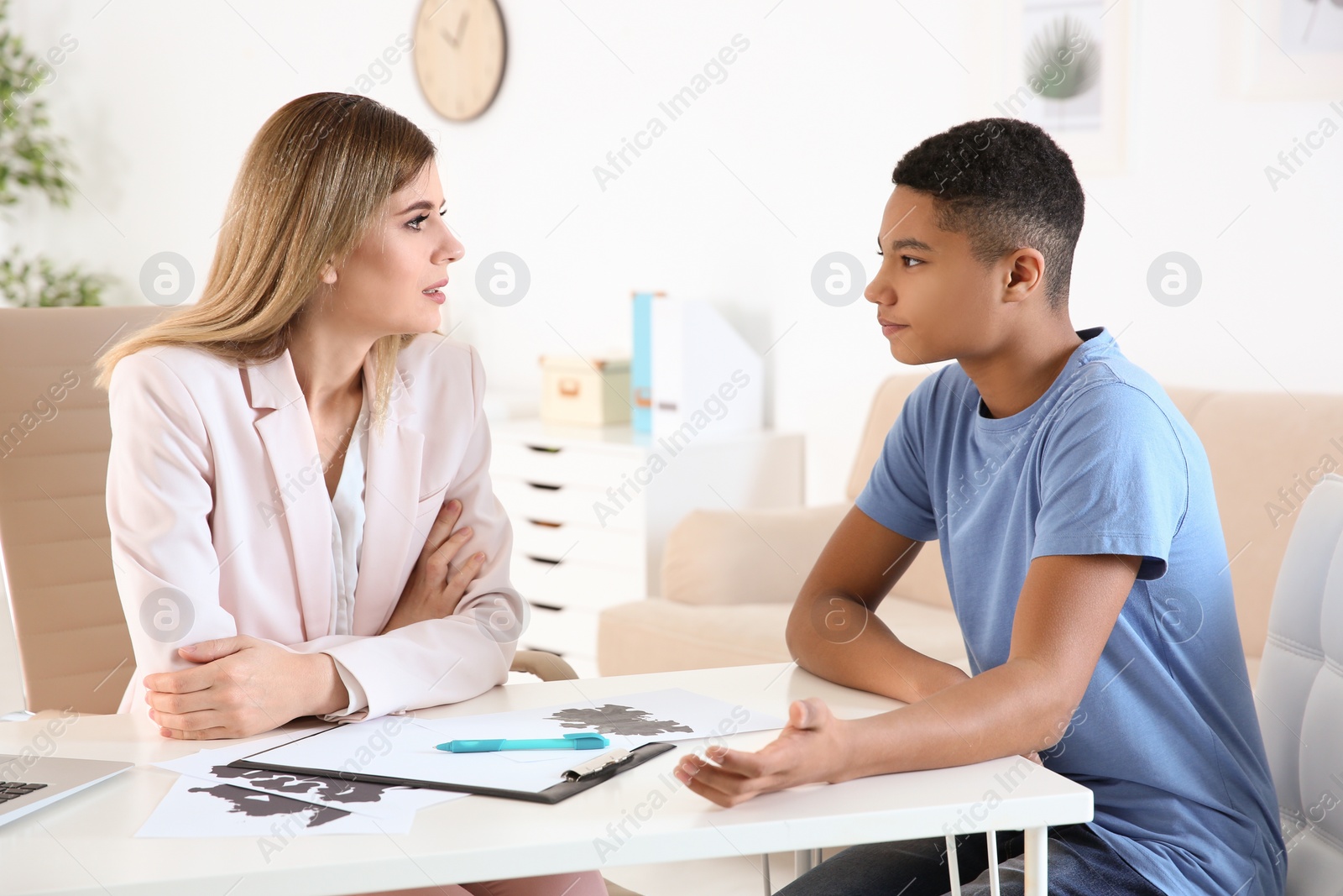 Photo of Female psychologist working with African American teenage boy in office