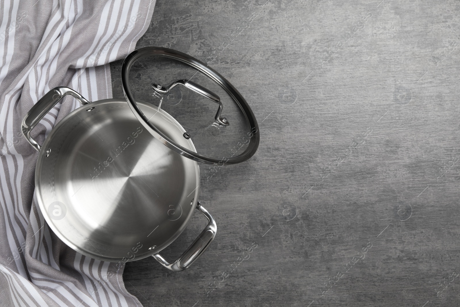 Photo of Cooking pot with lid on grey table, flat lay and space for text. Kitchen utensil