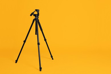 Modern tripod on yellow background. Space for text