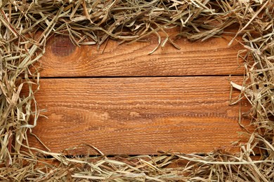 Photo of Frame made of dried hay on wooden background, top view. Space for text