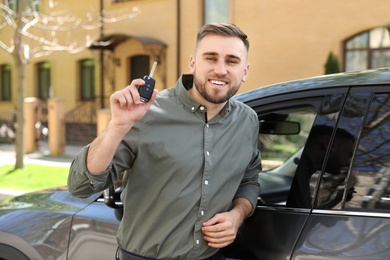 Image of Happy man with car key near his new auto outdoors