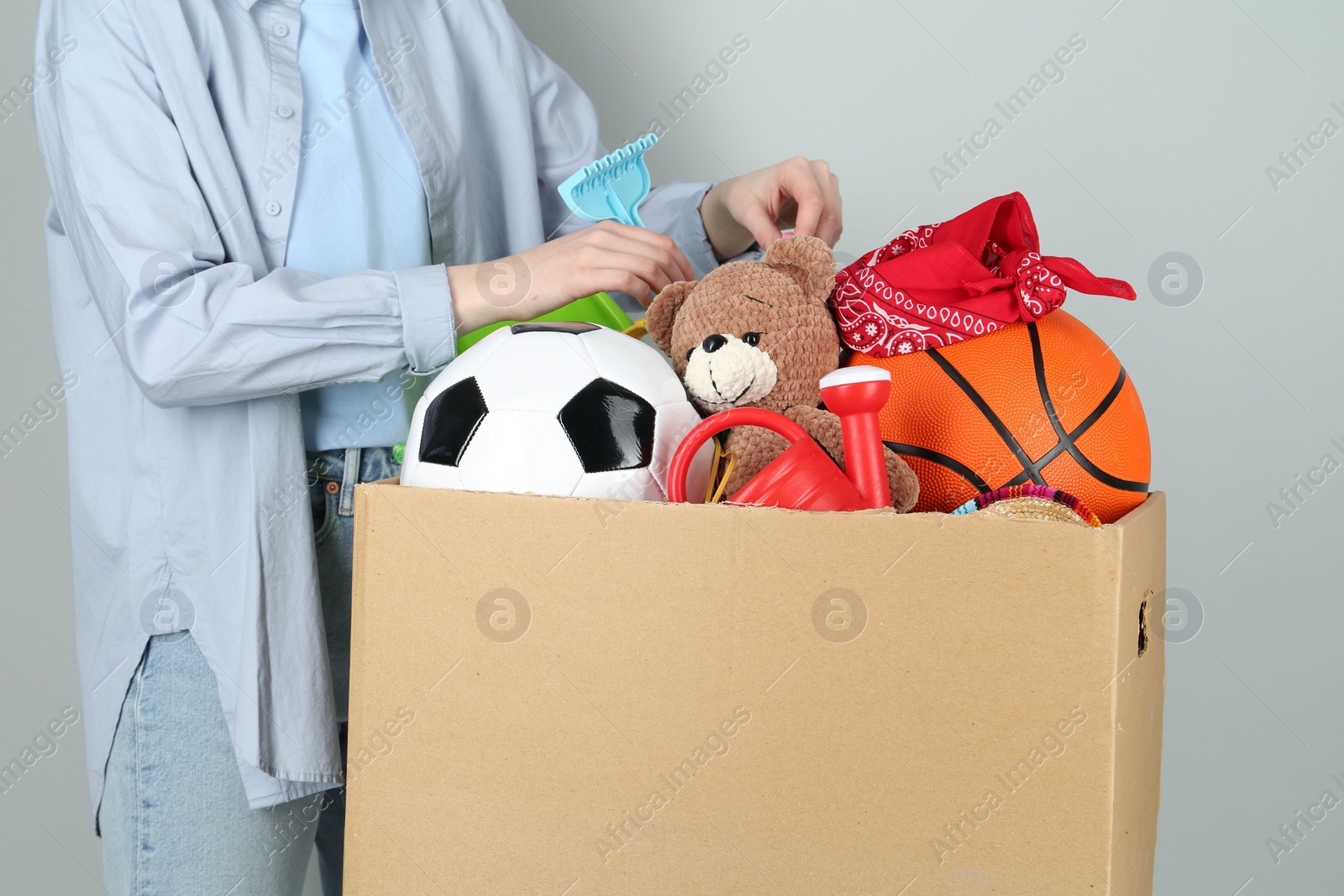 Photo of Woman with box of unwanted stuff on grey background, closeup