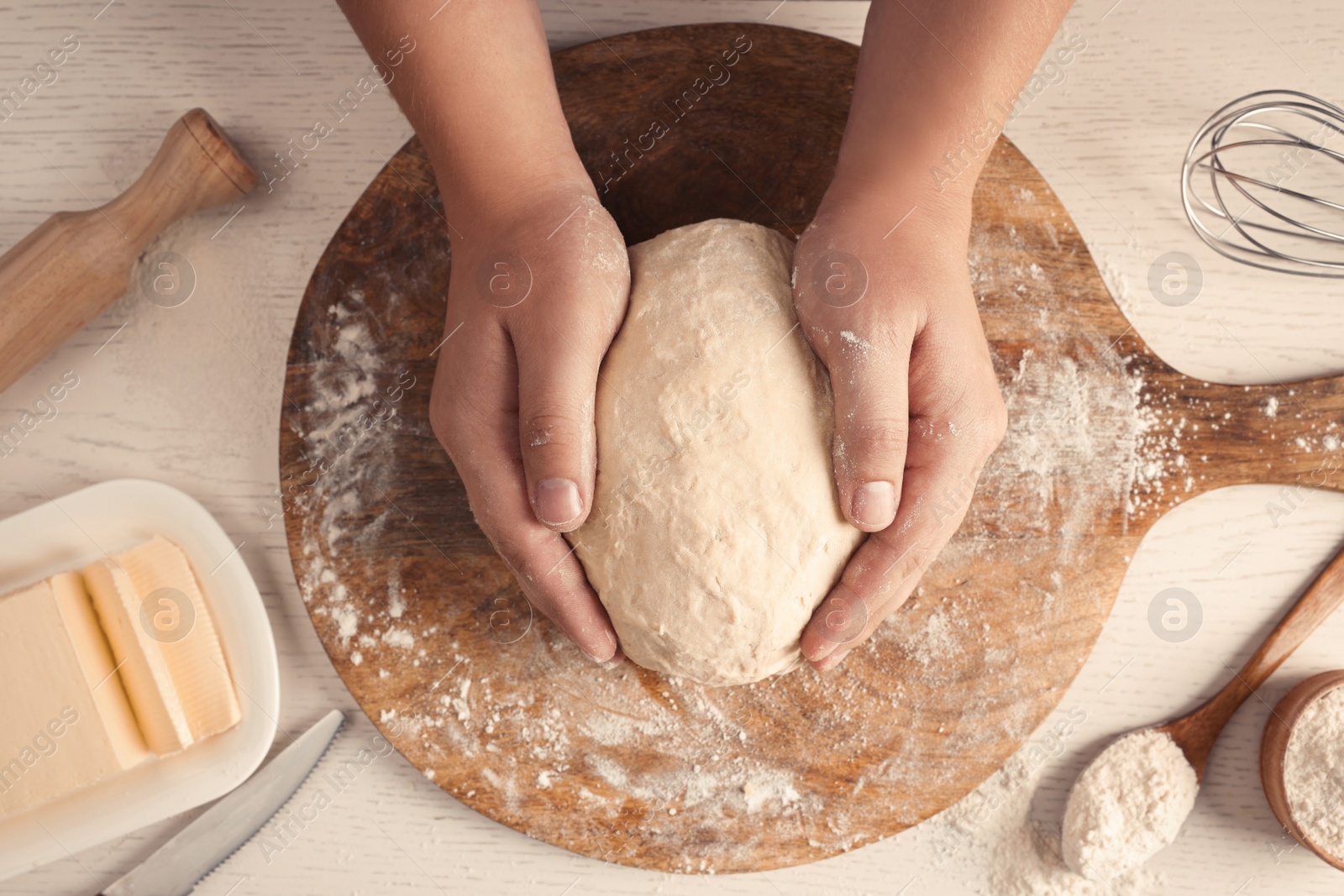 Photo of Man kneading dough at white wooden table, top view