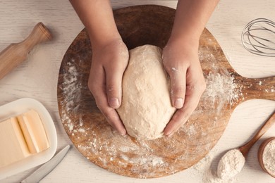 Man kneading dough at white wooden table, top view