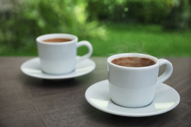 Photo of Cups of hot aromatic coffee on brown windowsill, space for text. Rainy weather