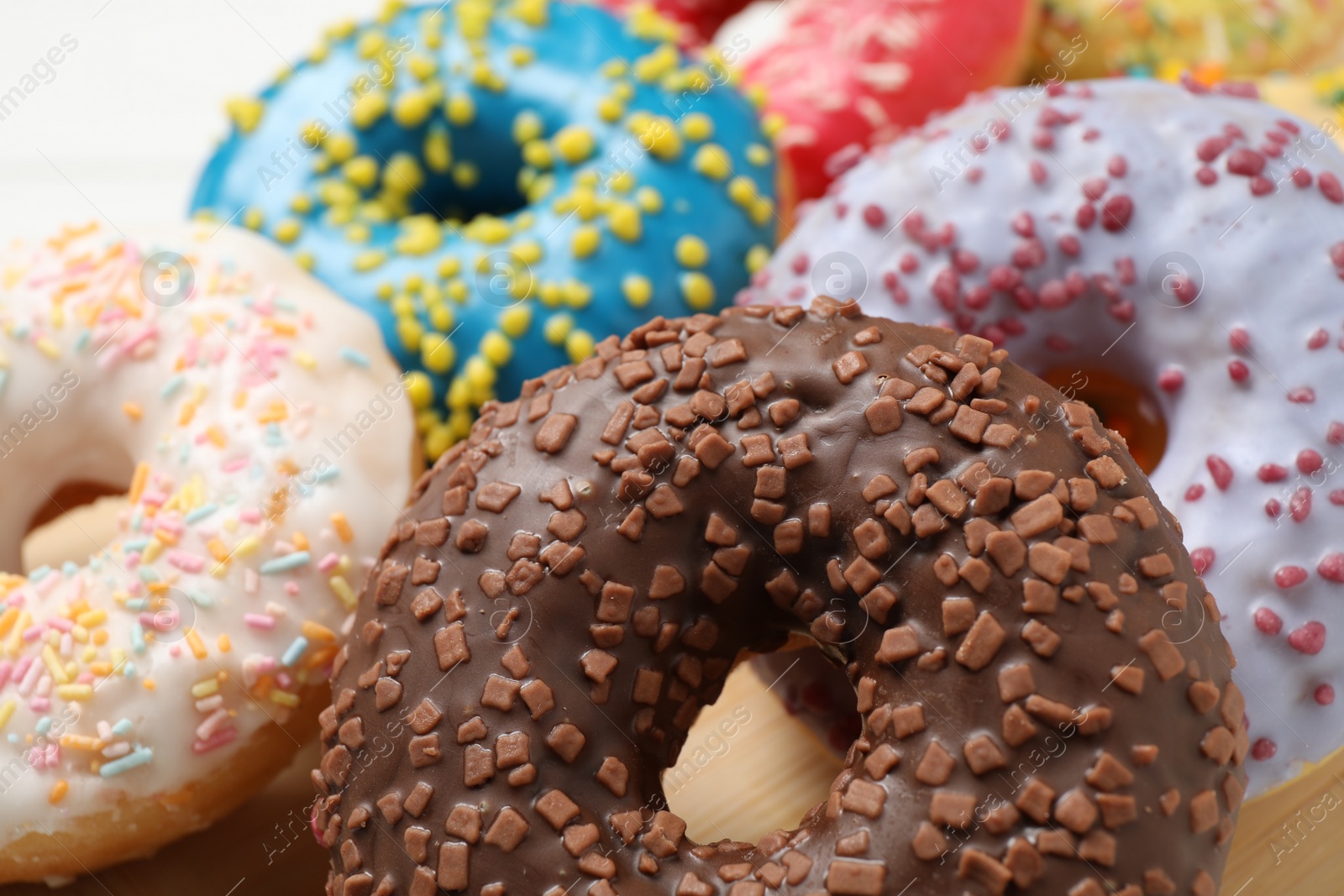 Photo of Yummy donuts with sprinkles on white table, closeup