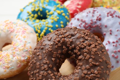 Yummy donuts with sprinkles on white table, closeup