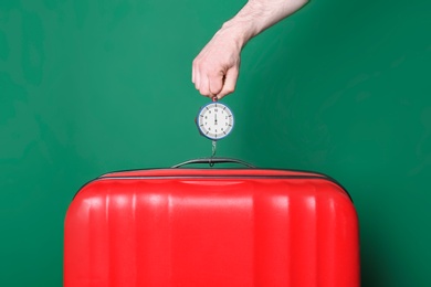 Photo of Man weighing stylish suitcase against color background, closeup