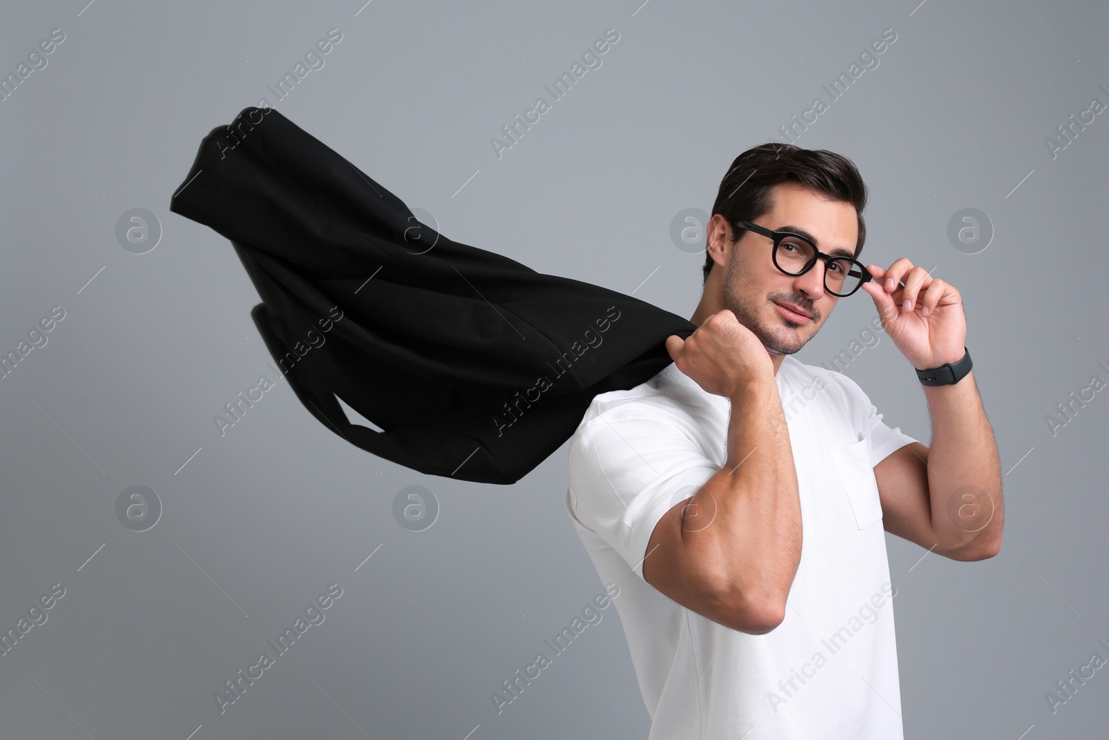 Photo of Handsome young man in casual clothes with black jacket and glasses on grey background