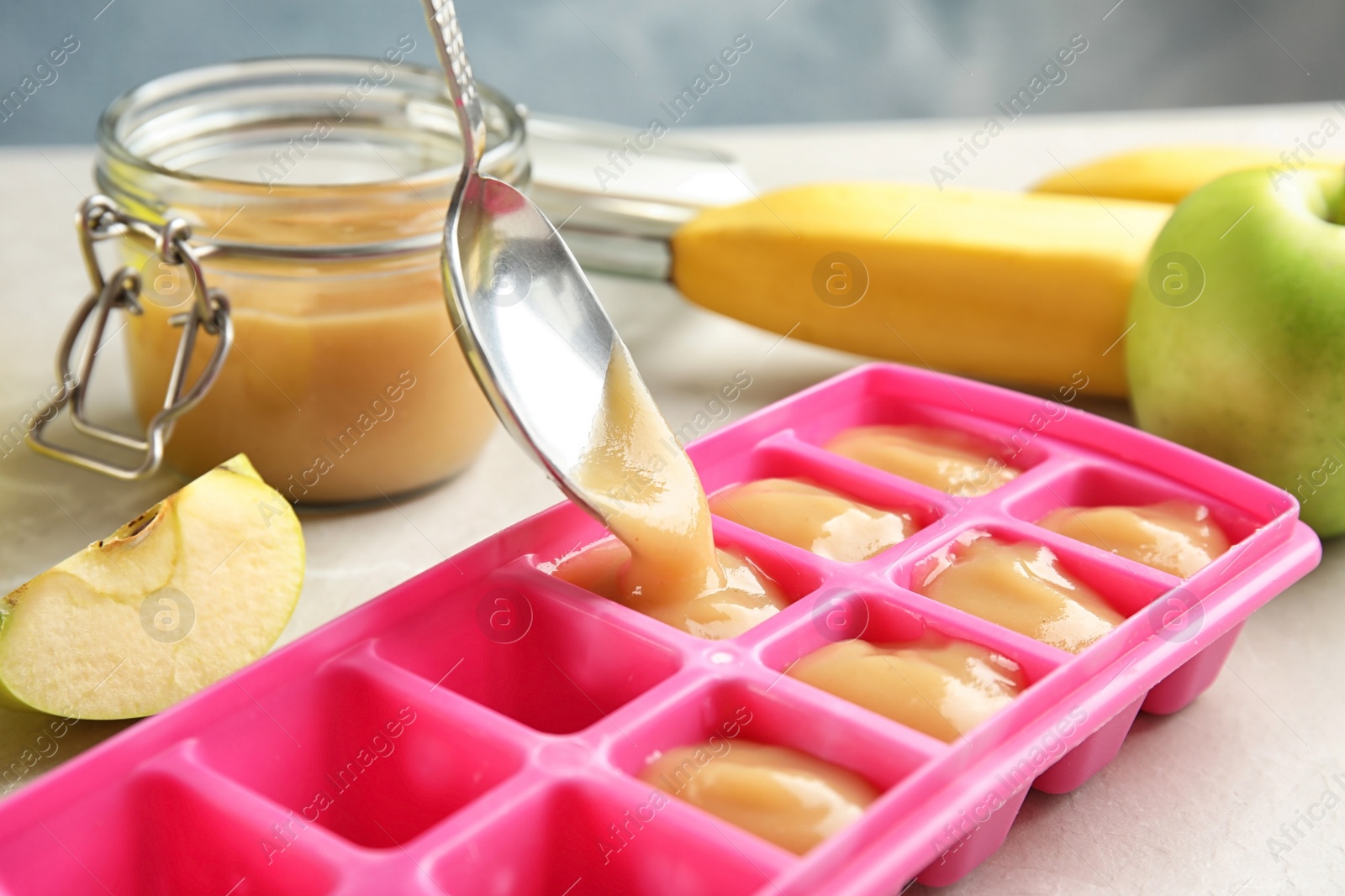 Photo of Putting healthy baby food into ice cube tray, closeup