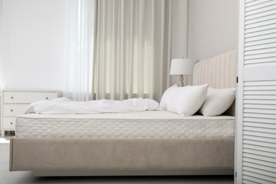 Photo of Comfortable bed with soft white mattress, blanket and pillows indoors