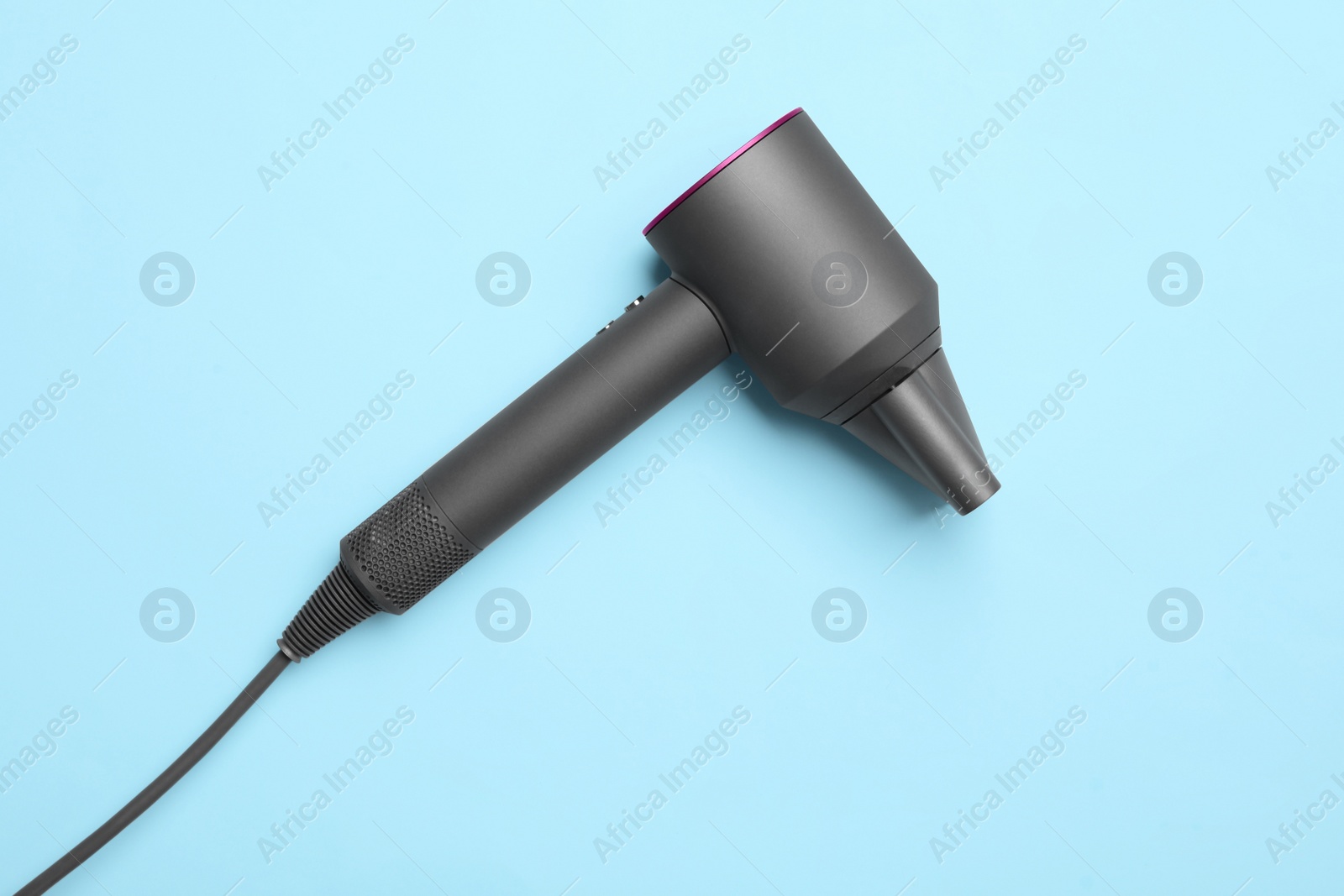 Photo of Hair dryer on light blue background, top view. Professional hairdresser tool