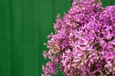Photo of Beautiful lilac flowers on green wooden background, closeup. Space for text