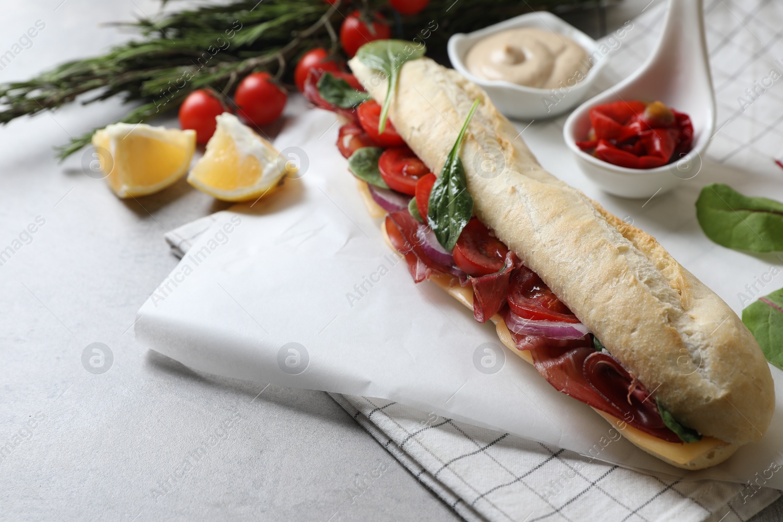 Photo of Delicious sandwich with bresaola served on light grey table