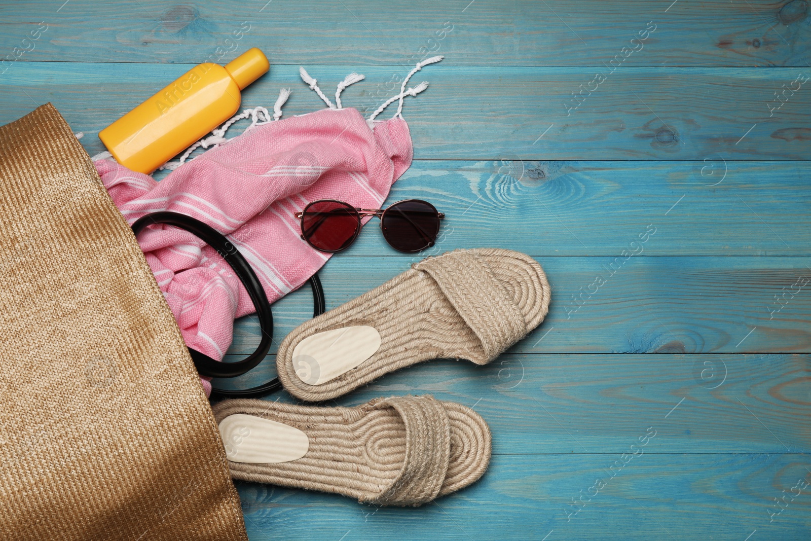 Photo of Stylish bag and beach accessories on blue wooden background, flat lay