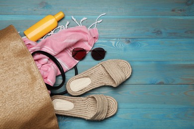 Stylish bag and beach accessories on blue wooden background, flat lay