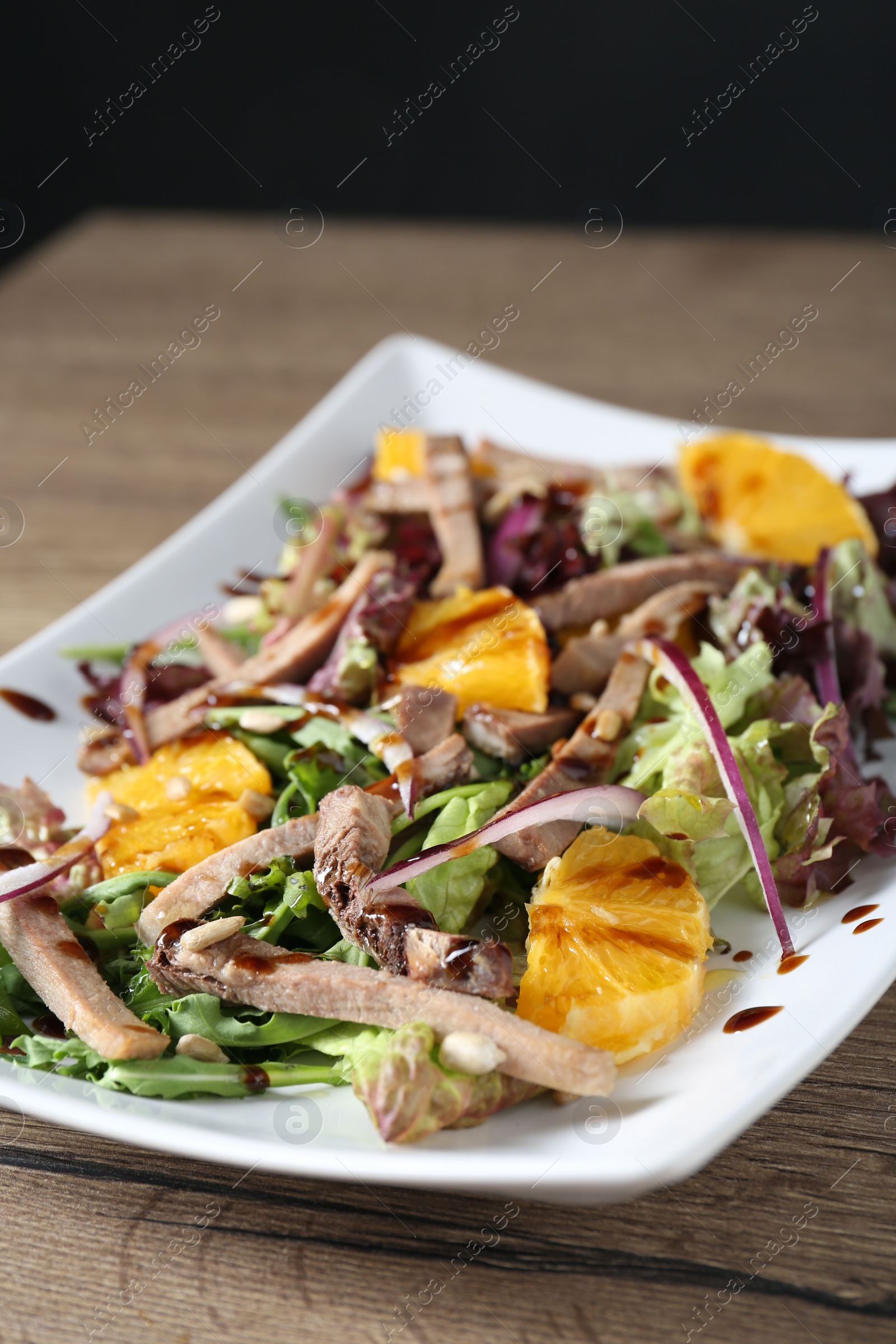Photo of Delicious salad with beef tongue, orange and onion on wooden table, closeup