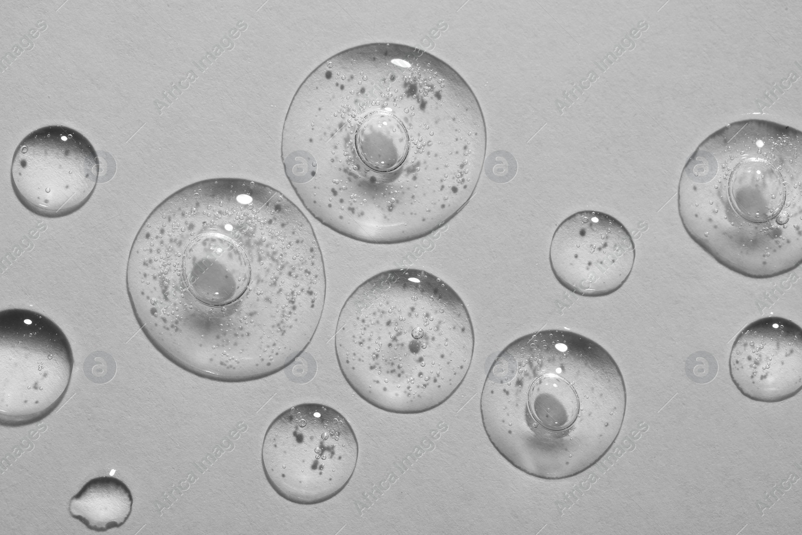 Photo of Drops of cosmetic serum on white background, top view