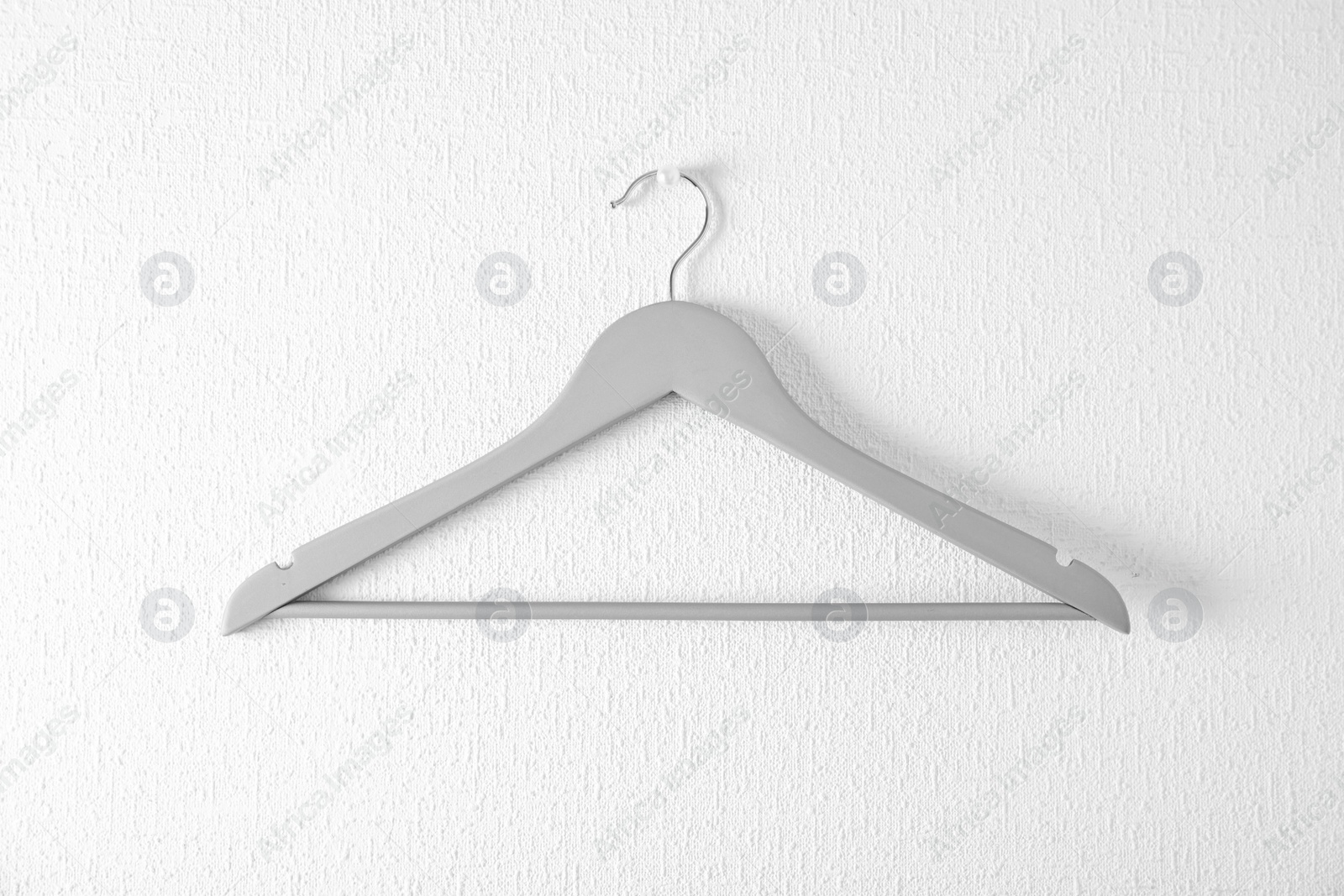 Photo of Empty clothes hanger on light wall. Wardrobe accessory