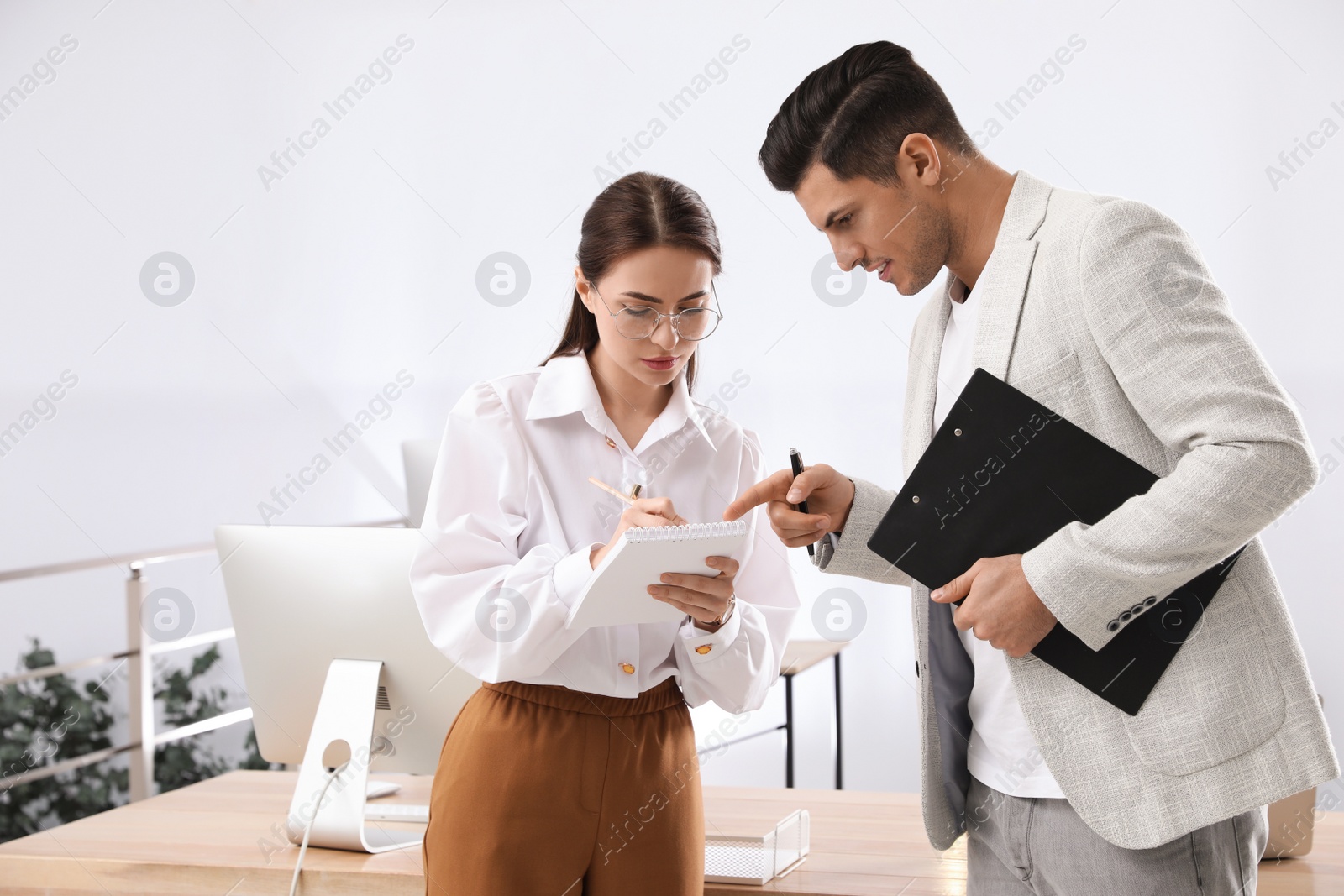 Photo of Businessman helping intern with work in office