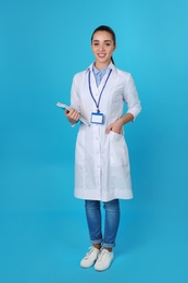 Young medical student with notebooks on color background