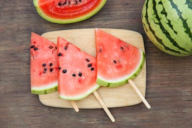 Photo of Whole and sliced delicious ripe watermelons on wooden table, flat lay