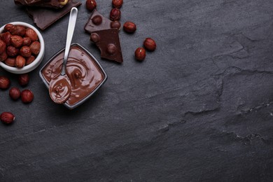 Photo of Bowl with tasty paste, chocolate pieces and nuts on black table, flat lay. Space for text