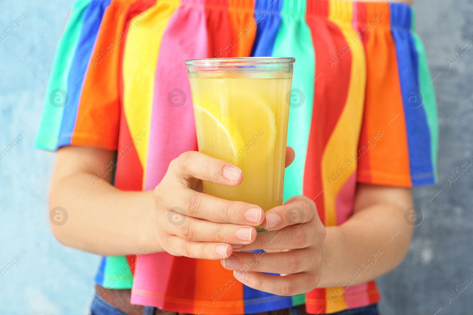 Photo of Young woman with glass of lemon juice on color background, closeup