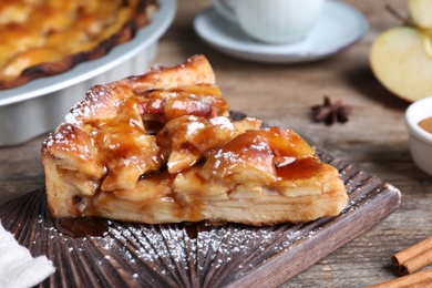 Photo of Slice of traditional apple pie served on wooden table, closeup