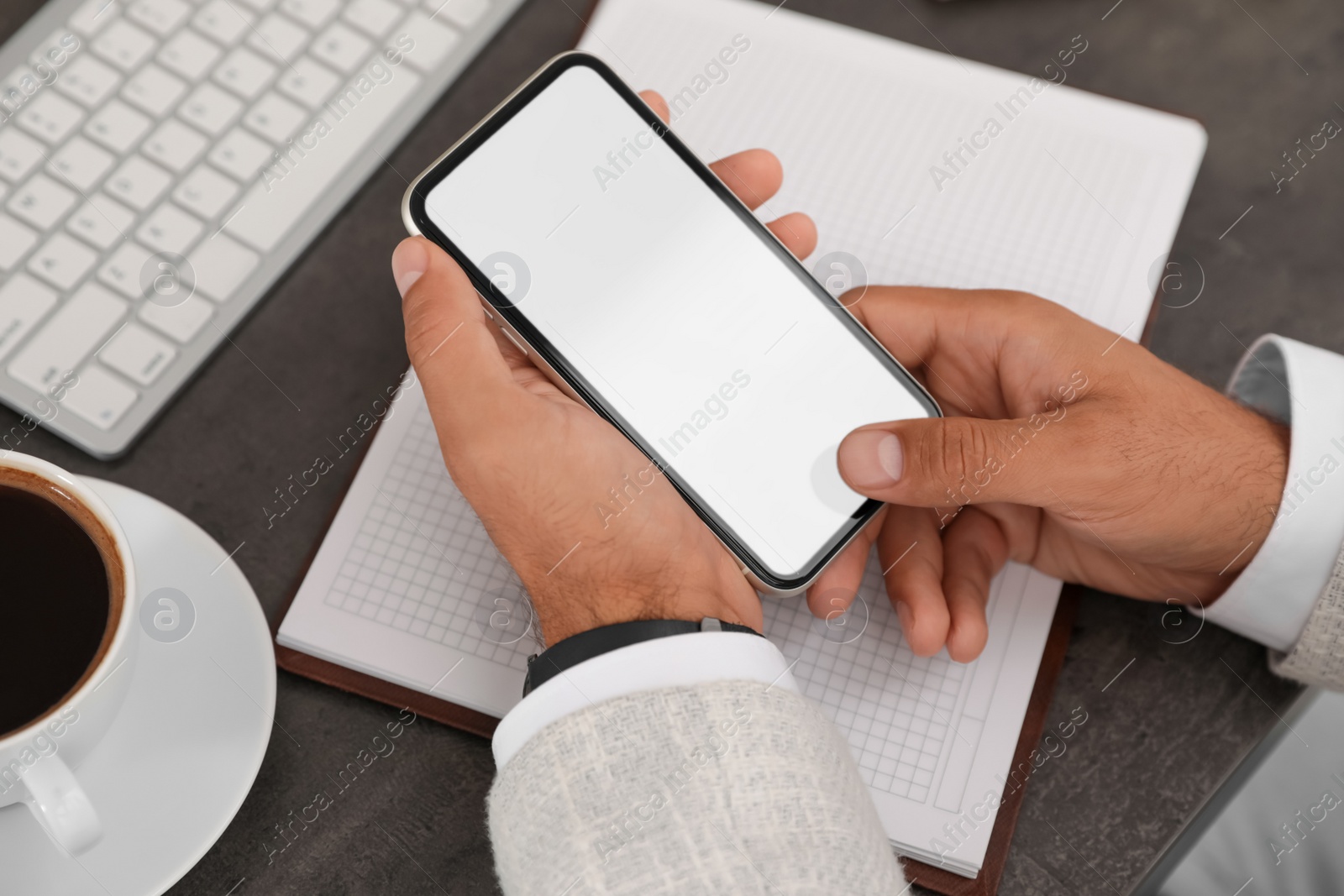 Photo of Man using mobile phone with empty screen at table, closeup