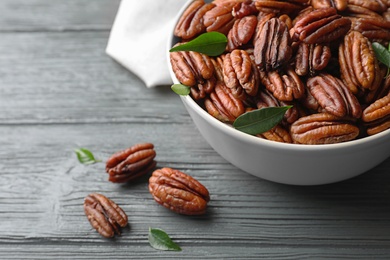 Dish with tasty pecan nuts on wooden table, closeup