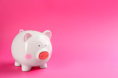 Photo of White piggy bank on pink background. Space for text