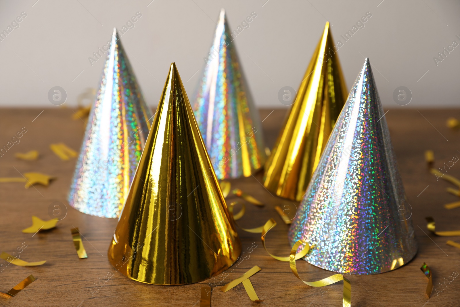 Photo of Birthday party hats, serpentine streamers and confetti on wooden table