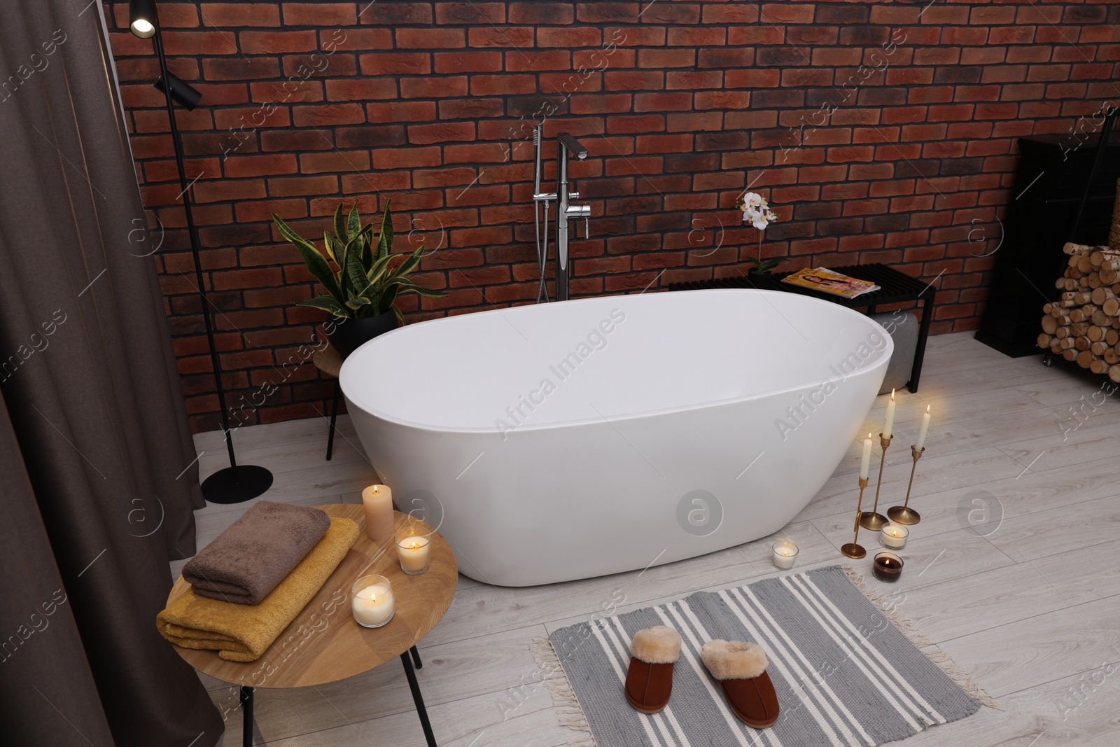 Photo of Stylish bathroom interior with ceramic tub and burning candles