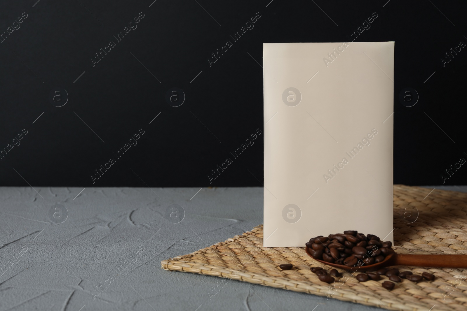 Photo of Scented sachet and coffee beans on grey table against black background, space for text