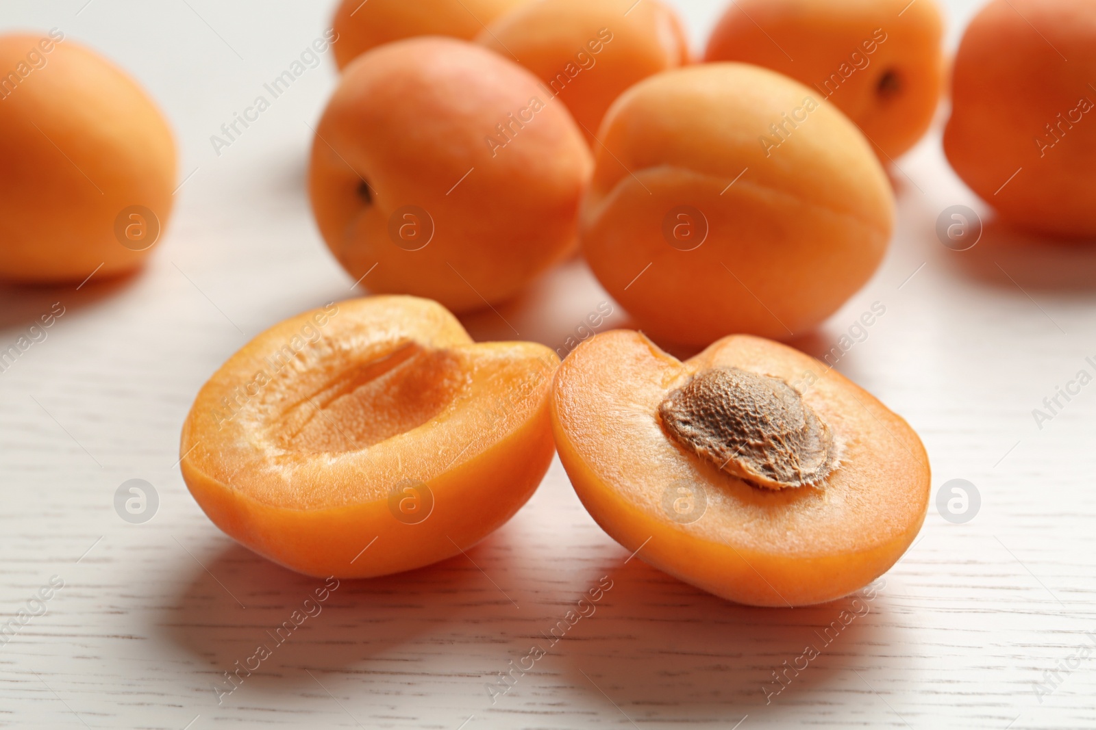 Photo of Delicious ripe sweet apricots on white wooden table, closeup view