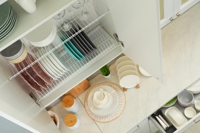 Clean plates, bowls and glasses on shelves in cabinet indoors