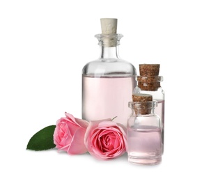Bottles of essential oil and roses on white background