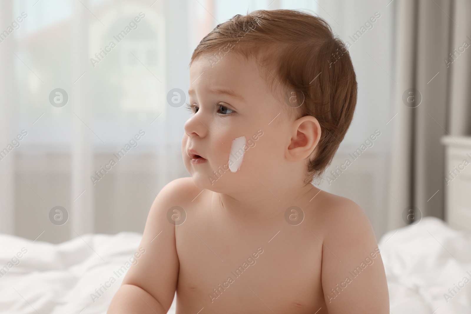 Photo of Cute little baby with cream on cheek indoors