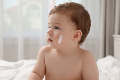 Photo of Cute little baby with cream on cheek indoors