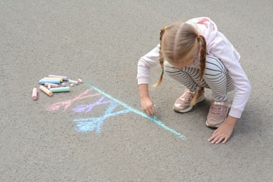 Photo of Little child drawing happy family with chalk on asphalt