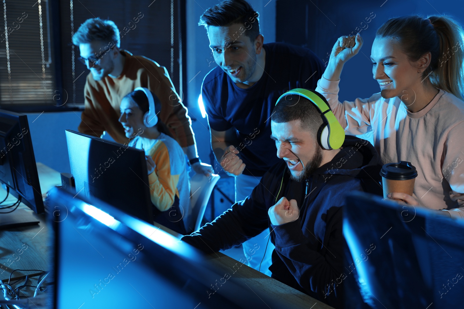 Photo of Group of people playing video games in internet cafe