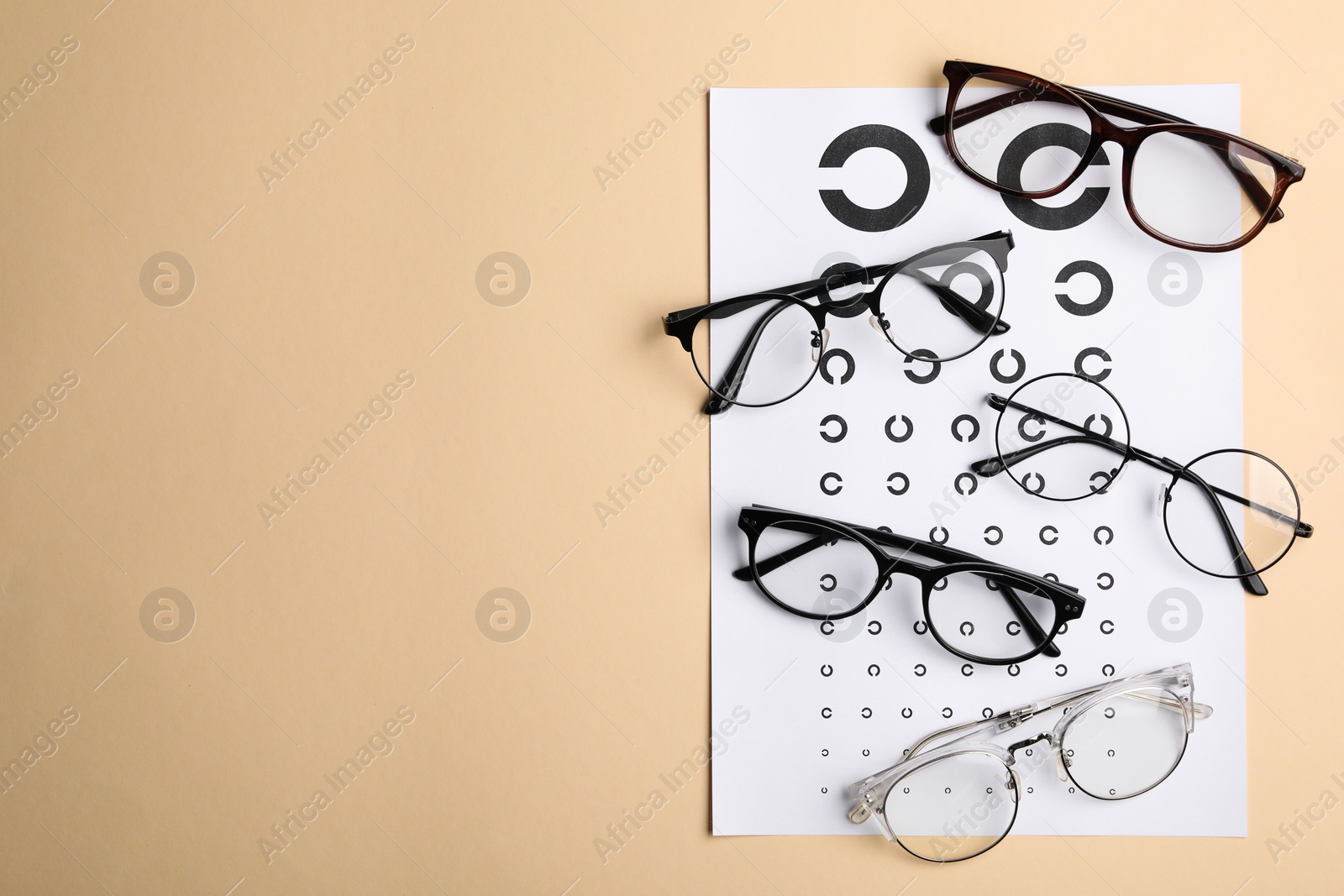 Photo of Vision test chart and glasses on beige background, flat lay. Space for text