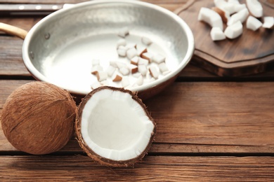 Photo of Frying pan with coconut pieces on wooden background