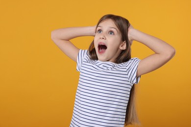 Portrait of surprised girl on yellow background