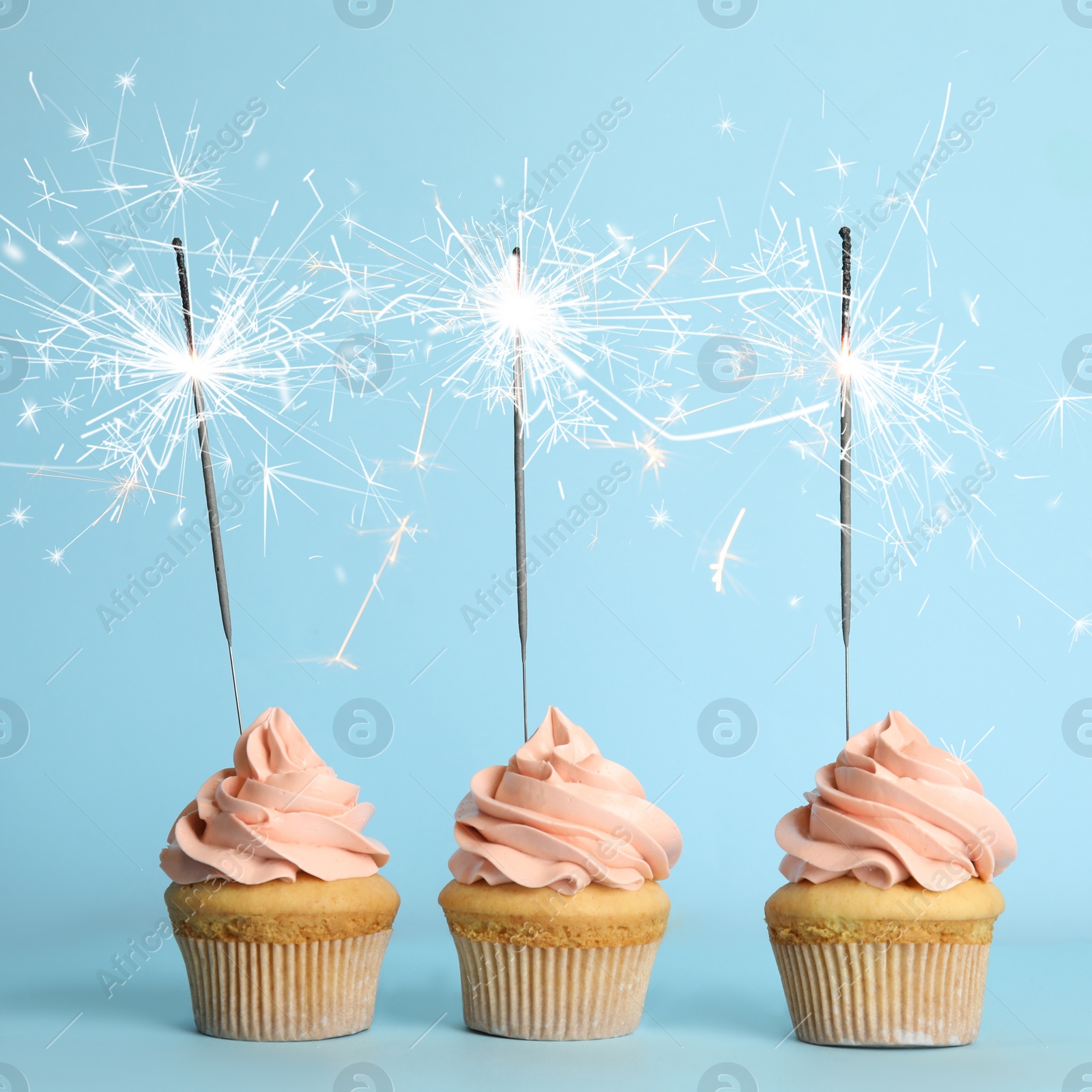 Image of Birthday cupcakes with sparklers on light blue background