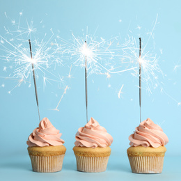 Image of Birthday cupcakes with sparklers on light blue background