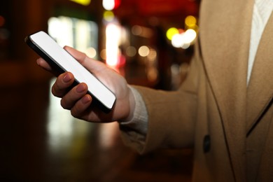 Photo of Woman with smartphone on night city street, closeup