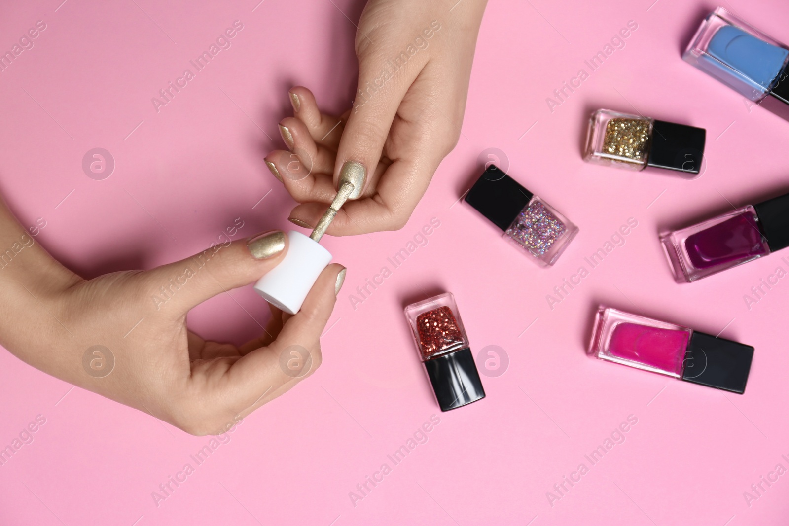 Photo of Woman applying nail polish on color background, top view